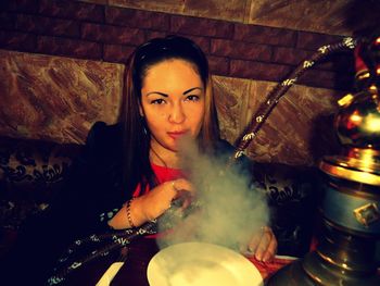 Portrait of young woman smoking hookah