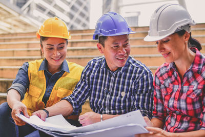 Architectures discussing blueprint while sitting on steps