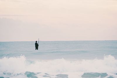 Man fishing in sea against sky