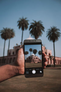 Man photographing through smart phone against sky