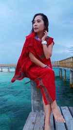 Portrait of beautiful woman standing by sea against sky