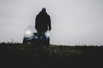 Rear view of man standing on field against sky