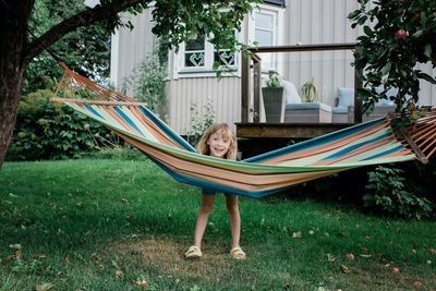 Young girl standing by a hammock smiling have fun in a garden at home