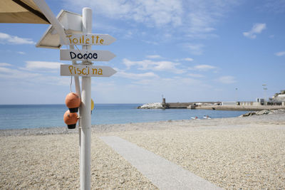 Information sign on beach against sky