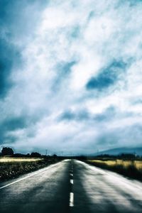 Road passing through landscape against cloudy sky