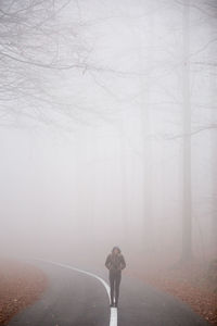 Full length of woman standing on road in foggy weather