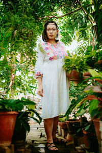 Portrait of young woman standing against plants