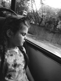 Girl with eyes closed sitting by window in bus
