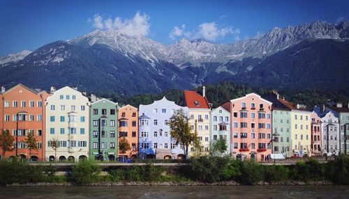 Colorful buildings and river against mountains on sunny day