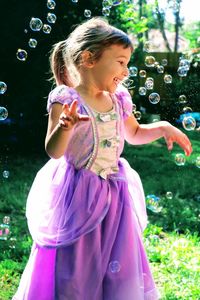 Cute little girl dressed like a princess playing with soap bubbles