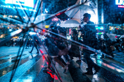 People on illuminated street in city at night