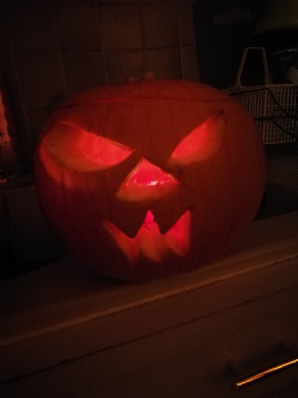 CLOSE-UP OF ILLUMINATED PUMPKIN AGAINST WALL