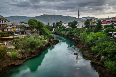 River amidst buildings in town against sky