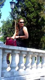 Portrait of woman with sunglasses on tree against plants