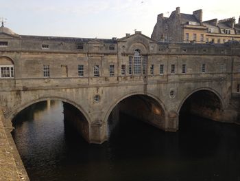 Arch bridge over river against buildings