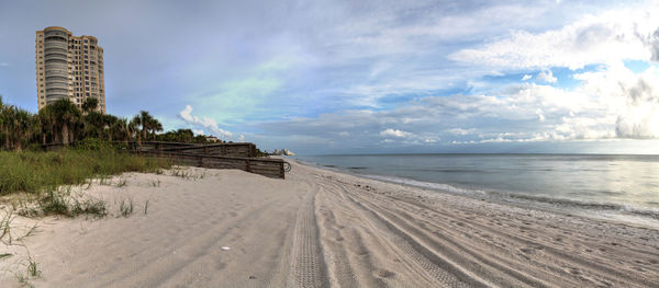 Panoramic sun peeks through the clouds over the ocean at sunset in naples, florida