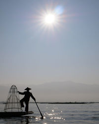 Silhouette man standing on sea against sky