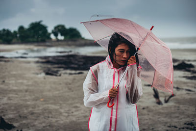 Full length of woman holding umbrella while standing on land