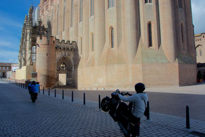 Men performing wheelie at albi cathedral