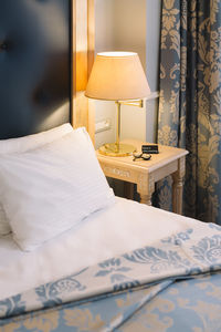 Vertical photo of bed with white pillow and bedside table in luxury hotel. on the table lamp