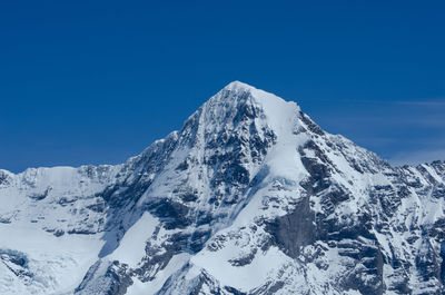 Scenic view of snowcapped mountains against clear blue sky