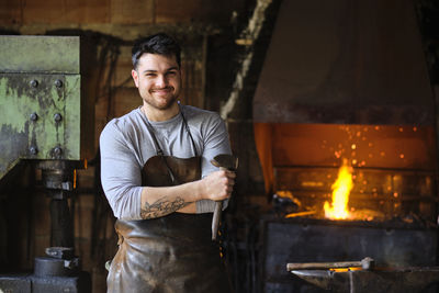 Portrait of young man standing against fire