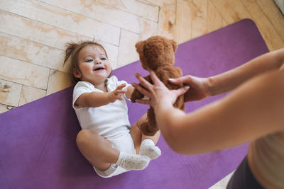 Young woman fit mom with baby girl doing fitness on mat at home