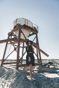 Low angle view of woman standing by metallic structure against sky