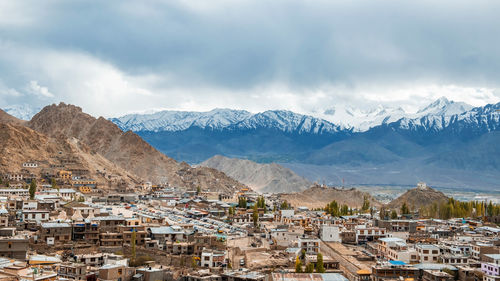 Aerial view of townscape and mountains against sky