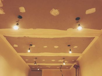 Low angle view of illuminated pendant lights hanging on ceiling in building