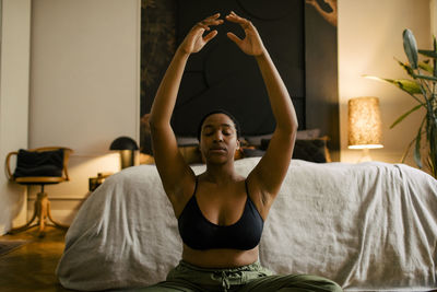 Young woman practicing breathing exercise in bedroom at home