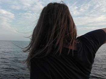 Beautiful woman standing by sea against sky