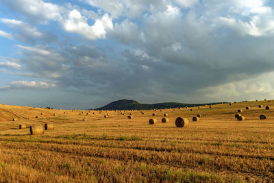 Hay bales on field against sky