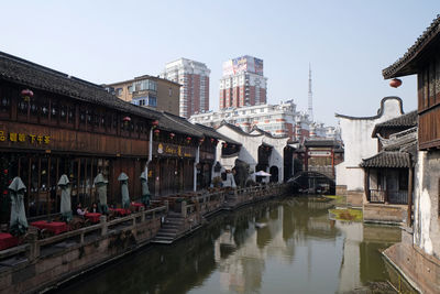 Bridge over canal amidst buildings against sky in city