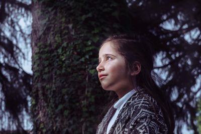 Happy woman standing by tree against blurred background