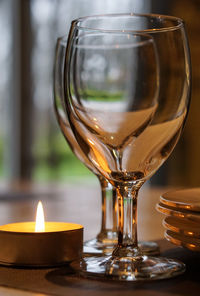 Close-up of tea light candle by wineglass on table in restaurant