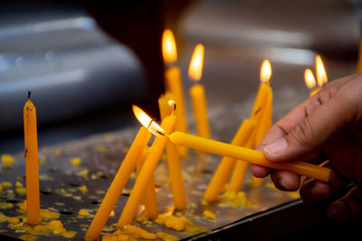 Midsection of person holding candles burning at temple