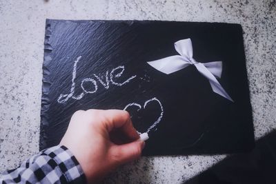 Cropped hand of person drawing heart shape on slate