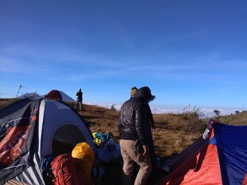 Rear view of men standing on tent against sky