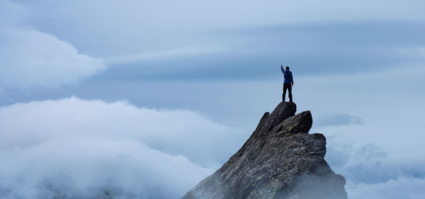 Man standing on rock against sky