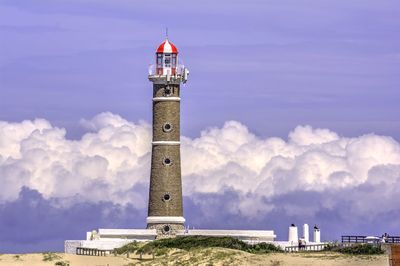 Lighthouse on building against cloudy sky
