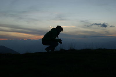 Silhouette of man photographing on field