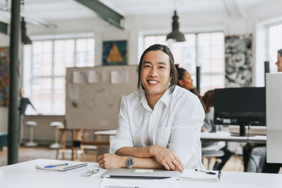 Portrait of smiling businessman at modern work place