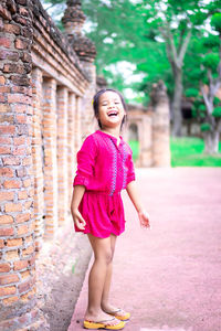 Full length of woman standing against pink wall