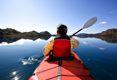 Woman rowing sea kayak on still lake in central iceland