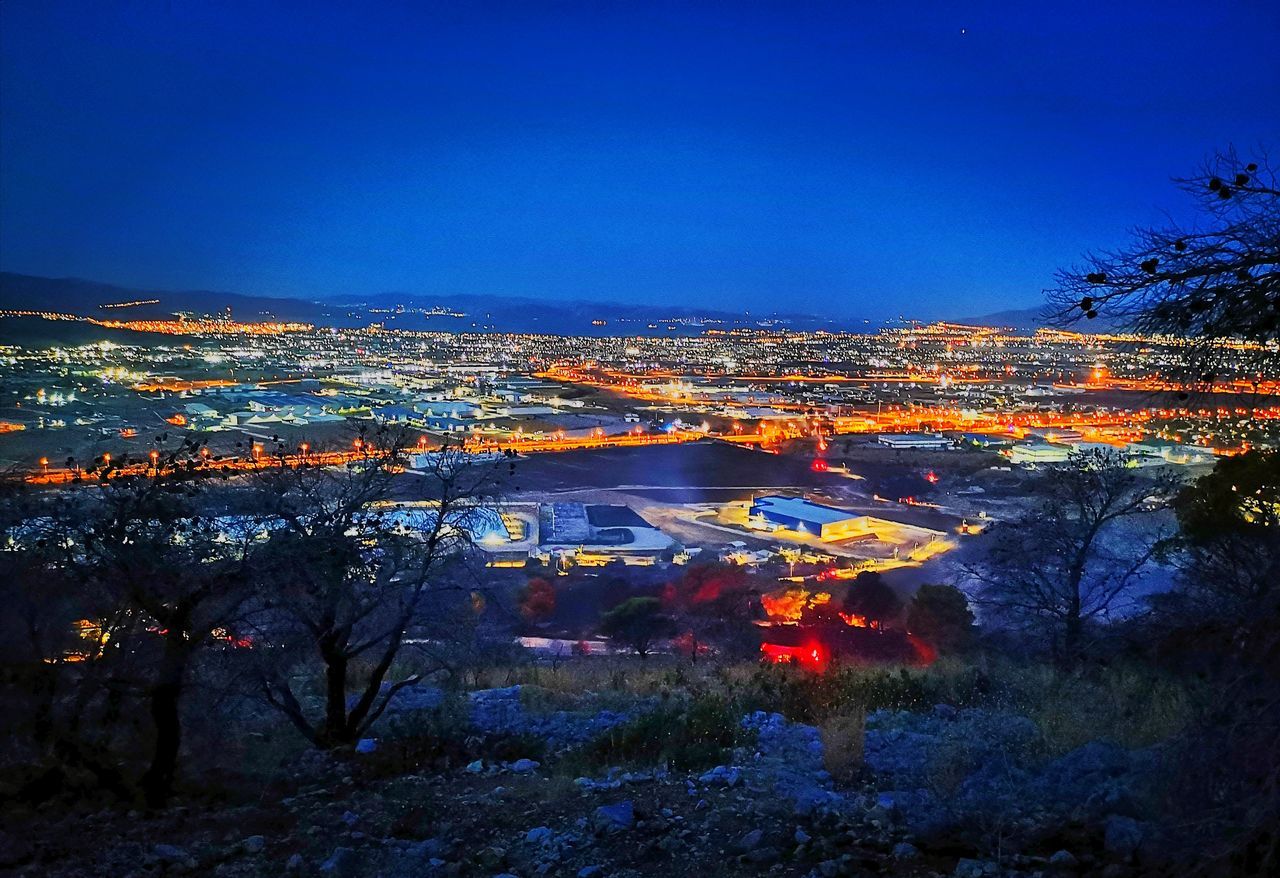 HIGH ANGLE VIEW OF ILLUMINATED CITY AT NIGHT