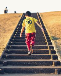 Rear view of boy running on steps