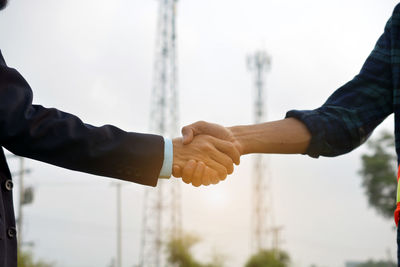 Midsection of man holding hands against clear sky