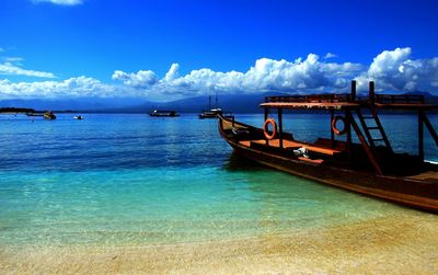 Boats in sea against cloudy sky