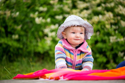 Close-up of cute baby girl sitting on blanket at park